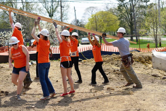 students help build home, lifting rafter together