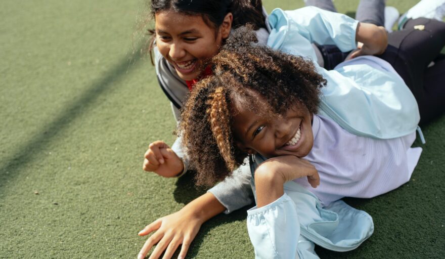 two children smiling happily on ground