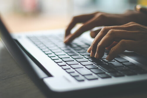 Close-up of hands typing on laptop