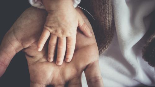 Baby hand placed on top of parents hand