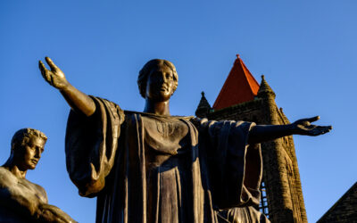 Statue with outstretched arms against a blue sky