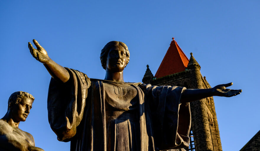 Statue with outstretched arms against a blue sky